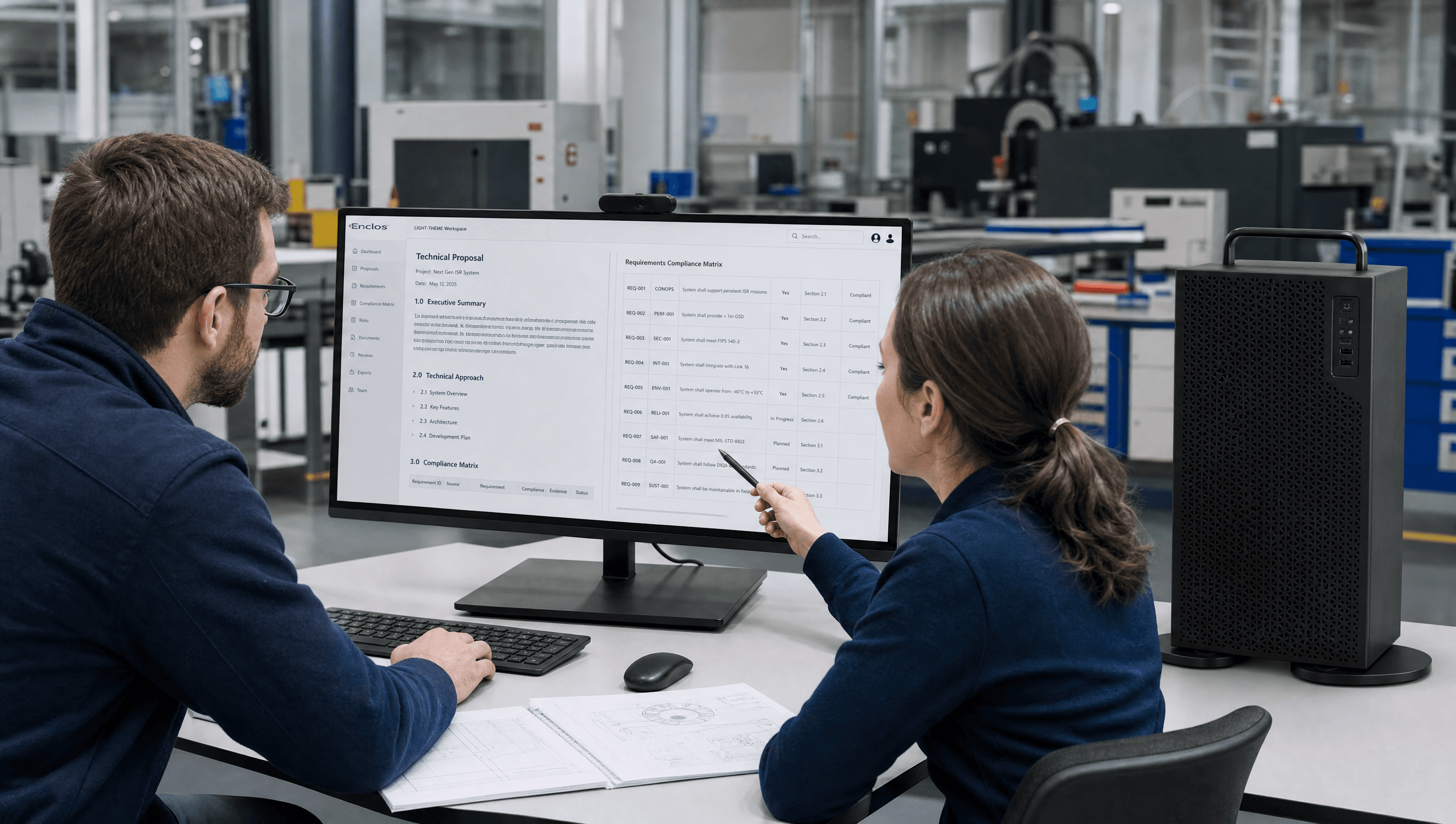 Two engineers reviewing the Enclos workspace on a monitor in a defense facility